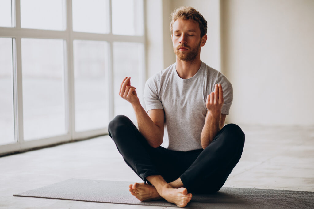Image d'un homme sur un tapis de yoga, concentré sur sa respiration